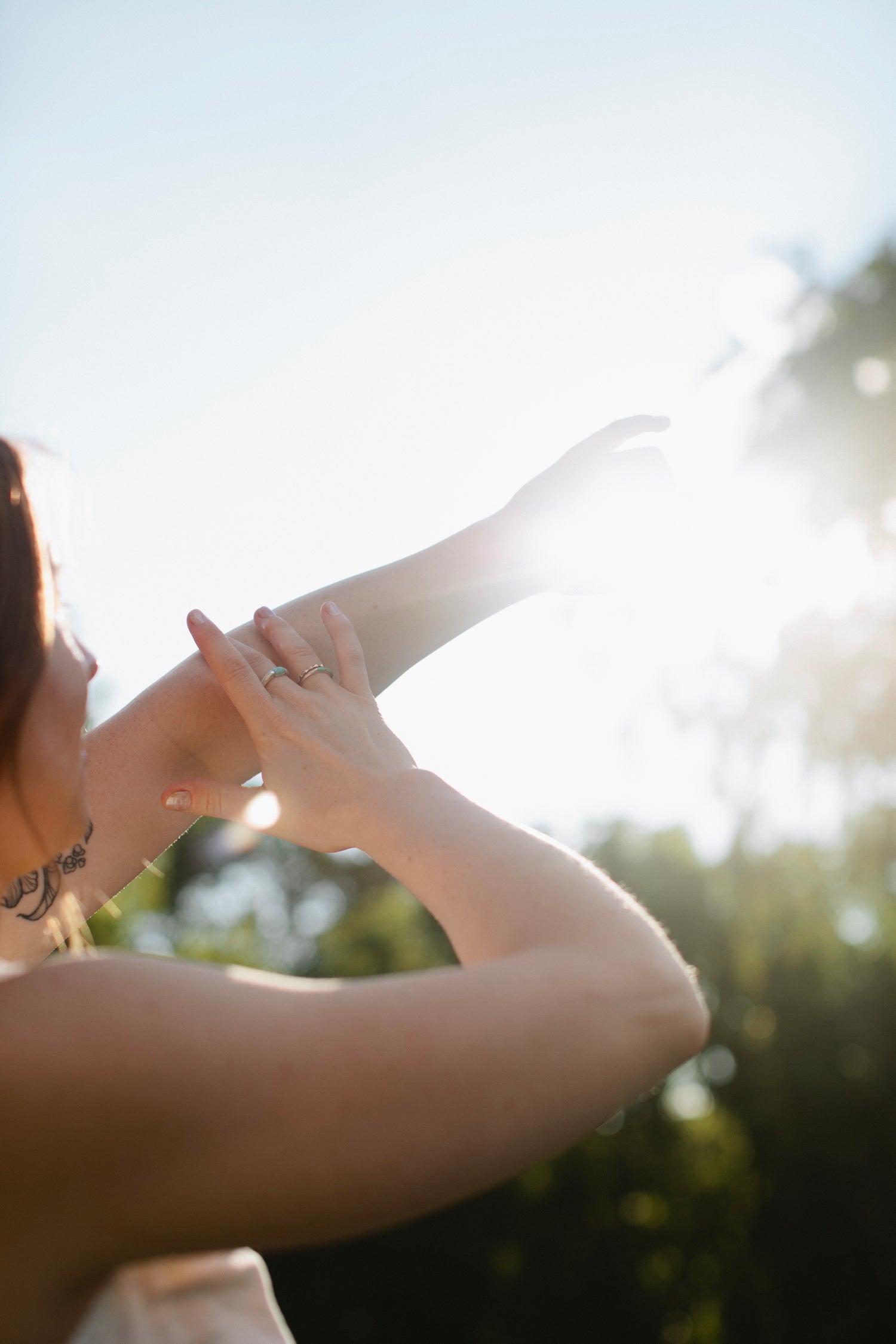 Person holding applying body oil outdoors with bright sun in background